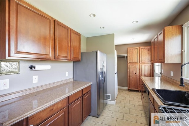 63 W Iselin Pkwy, Iselin, NJ 08830 - kitchen with stainless steel fridge, brown cabinetry, light tile patterned floors, recessed lighting, and light stone countertops