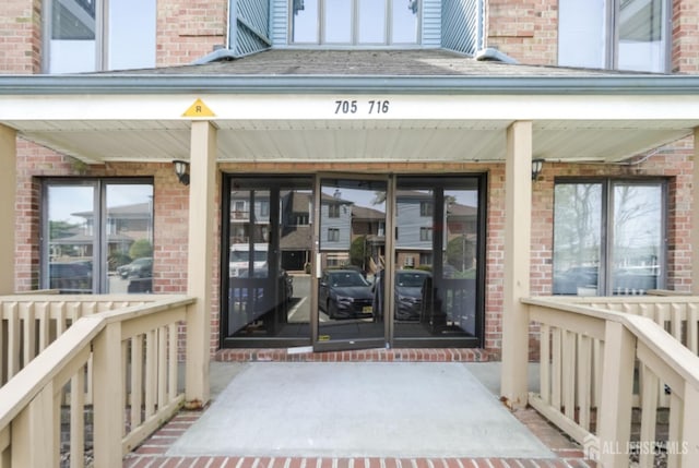 entrance to property with covered porch and brick siding