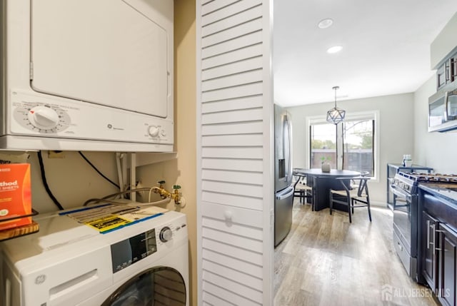 laundry room with recessed lighting, stacked washer / drying machine, laundry area, and light wood-style floors