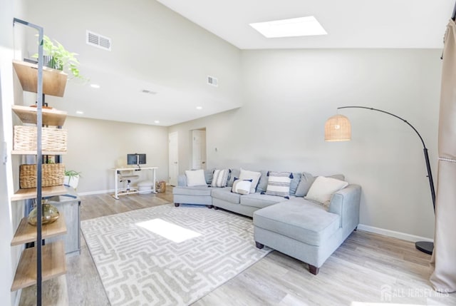 living area with a skylight, baseboards, light wood-style floors, and visible vents