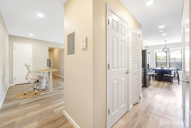 hall featuring baseboards, electric panel, recessed lighting, and light wood-style flooring