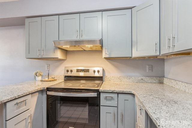 kitchen with light stone counters, gray cabinets, under cabinet range hood, and stainless steel electric stove