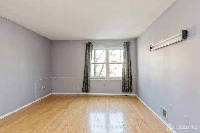 spare room featuring visible vents, baseboards, and wood finished floors