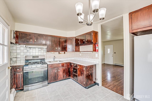 kitchen featuring gas stove, baseboard heating, a sink, a chandelier, and light countertops