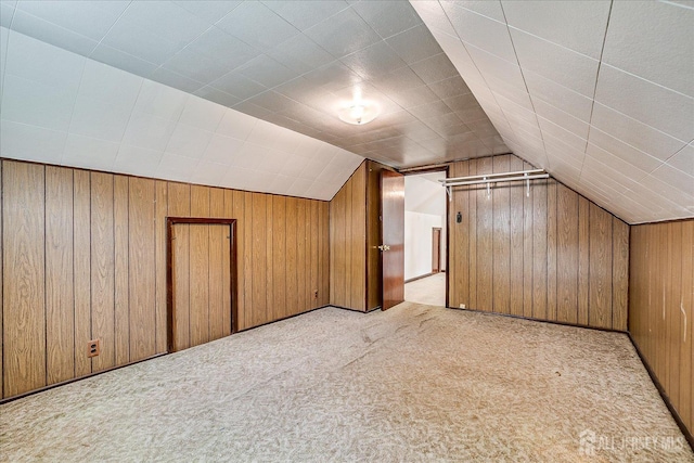 additional living space with wood walls, light colored carpet, and vaulted ceiling