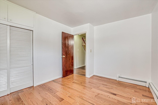 137 Grand Ave, Iselin, NJ 08830 - unfurnished bedroom featuring light wood-style floors, a closet, a baseboard heating unit, and baseboards