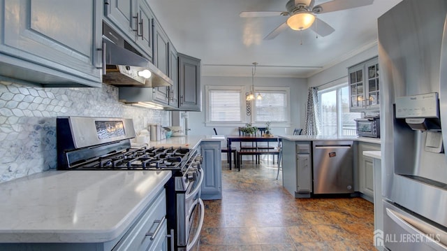 kitchen with gray cabinetry, hanging light fixtures, stainless steel appliances, under cabinet range hood, and backsplash