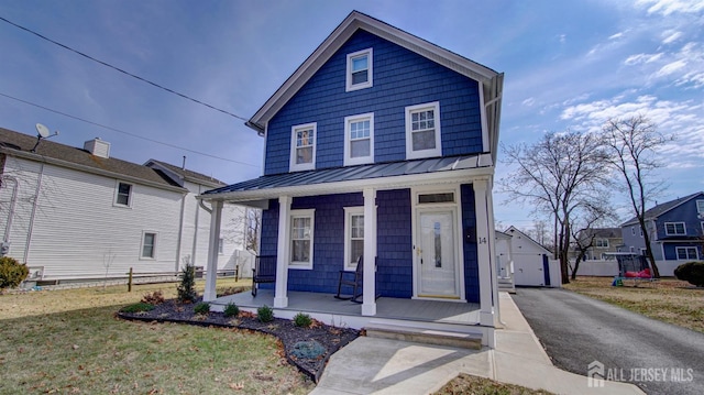 view of front of property featuring a standing seam roof, an outbuilding, and covered porch