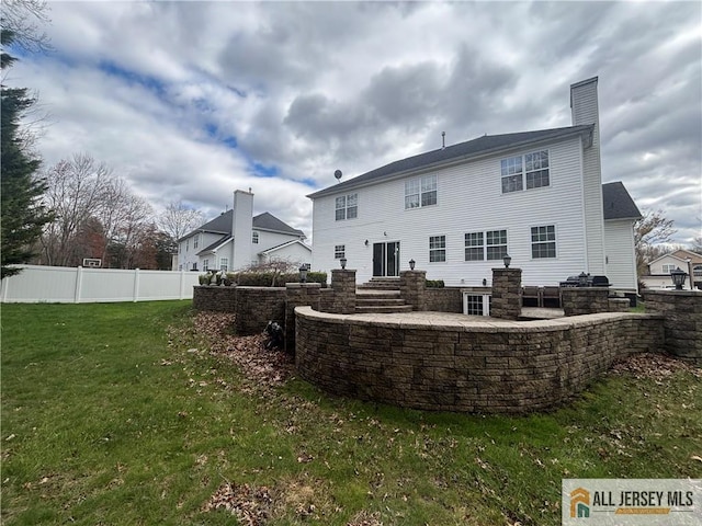 rear view of property featuring fence, a lawn, and a chimney