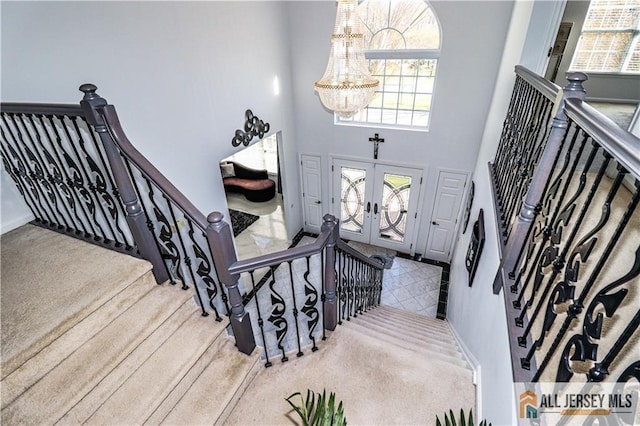 stairs featuring an inviting chandelier, french doors, a towering ceiling, and carpet