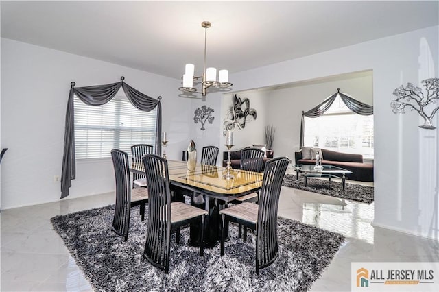 dining space featuring marble finish floor and a chandelier