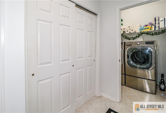 clothes washing area featuring baseboards, independent washer and dryer, laundry area, and light tile patterned floors