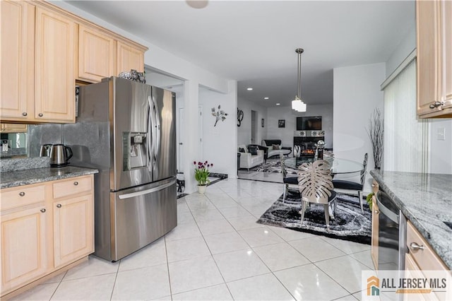 kitchen featuring stainless steel appliances, open floor plan, stone counters, backsplash, and light brown cabinets