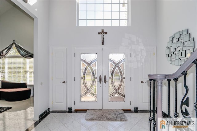 foyer entrance featuring baseboards, french doors, and a towering ceiling
