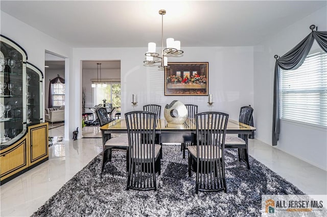 dining room with marble finish floor and a chandelier