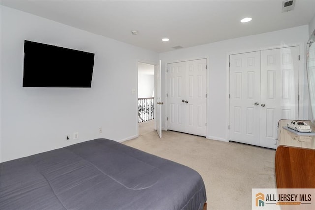 bedroom featuring recessed lighting, multiple closets, visible vents, baseboards, and light colored carpet