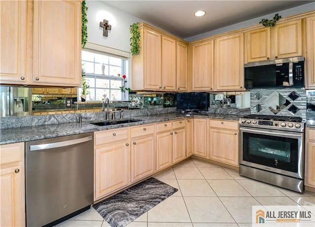 kitchen featuring tasteful backsplash, a sink, light brown cabinetry, light tile patterned floors, and stainless steel appliances