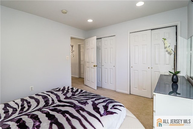 bedroom with recessed lighting, multiple closets, and light colored carpet