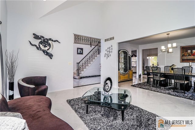 living area featuring stairway, marble finish floor, visible vents, baseboards, and a notable chandelier