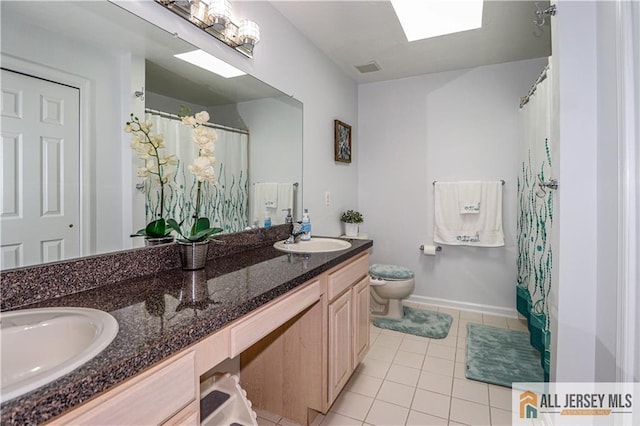 bathroom featuring tile patterned floors, a sink, double vanity, and toilet