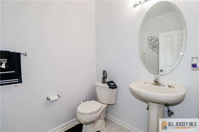 half bathroom featuring tile patterned flooring, toilet, and baseboards