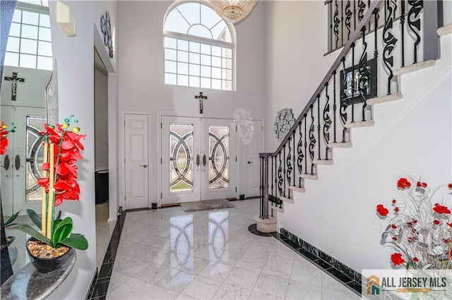 foyer entrance featuring marble finish floor, stairs, a towering ceiling, and baseboards