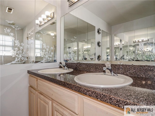 bathroom featuring visible vents, a sink, and double vanity