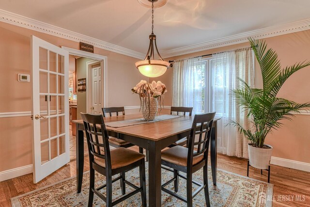 dining area with wood-type flooring, crown molding, and french doors