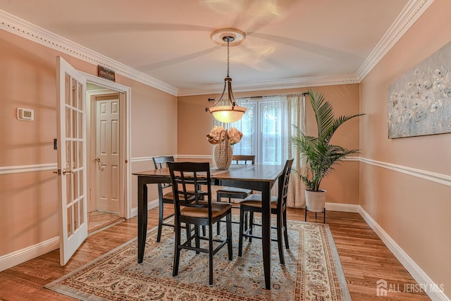 dining space featuring crown molding, hardwood / wood-style floors, and french doors