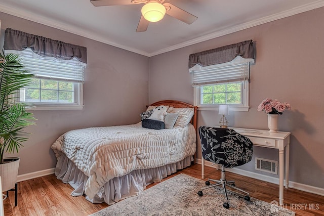 bedroom with ceiling fan, wood-type flooring, ornamental molding, and multiple windows