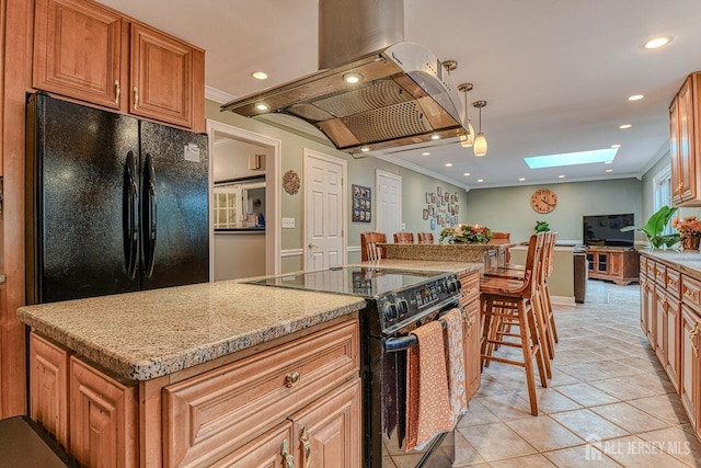 kitchen featuring a skylight, island range hood, black appliances, pendant lighting, and a center island