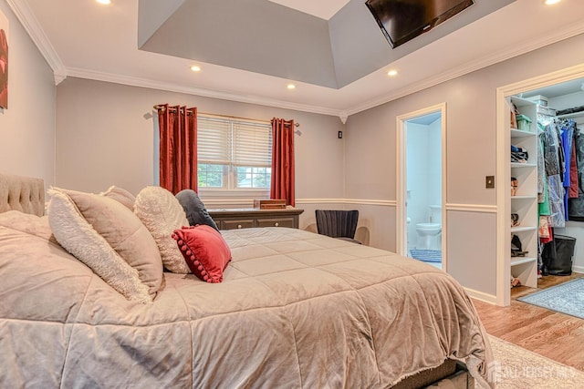 bedroom with a raised ceiling, ensuite bath, a spacious closet, light hardwood / wood-style floors, and a closet