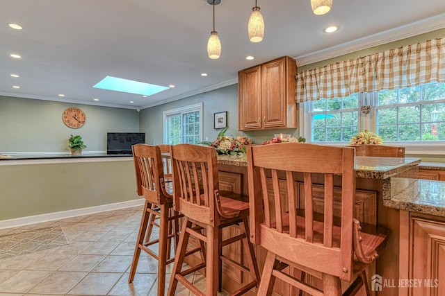 tiled dining area featuring a healthy amount of sunlight, ornamental molding, and a skylight