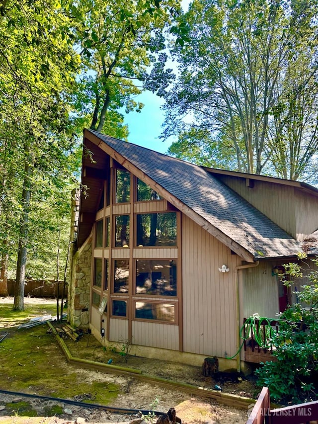 view of side of home with roof with shingles