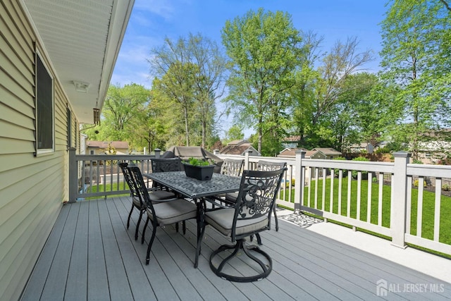 wooden deck featuring outdoor dining space and a yard