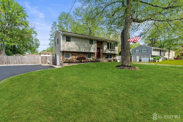 raised ranch with driveway, a garage, and brick siding
