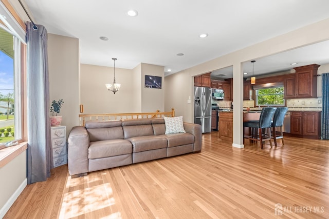 living room featuring light wood-style floors, a chandelier, baseboards, and recessed lighting