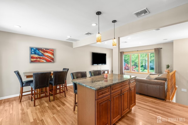 kitchen featuring open floor plan, light wood finished floors, a kitchen bar, and recessed lighting