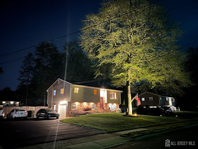 view of front facade featuring asphalt driveway, a garage, and a yard