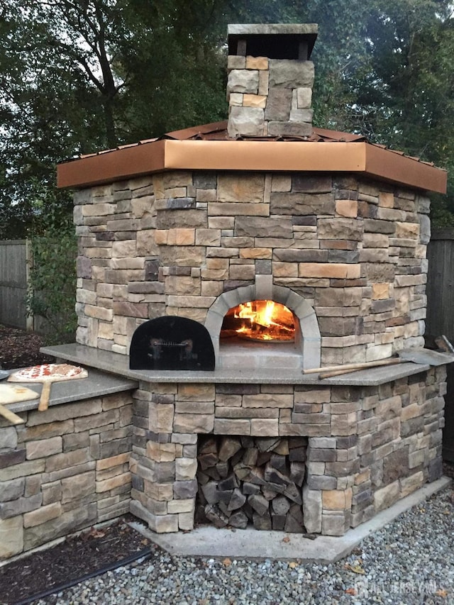 exterior view of an outdoor stone fireplace and fence