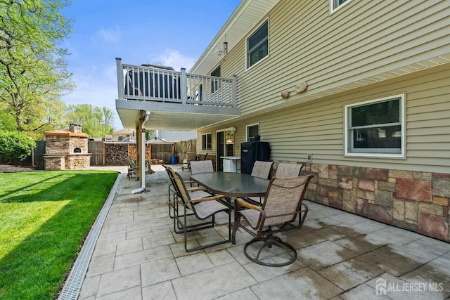 view of patio featuring a fireplace, outdoor dining area, and a balcony