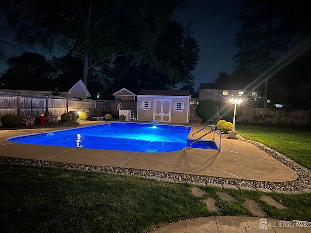 pool at night with a storage shed and an outdoor structure