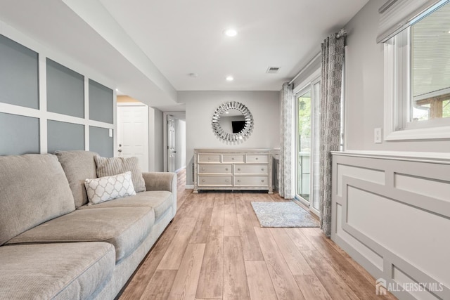 living area with light wood-style floors, plenty of natural light, and recessed lighting