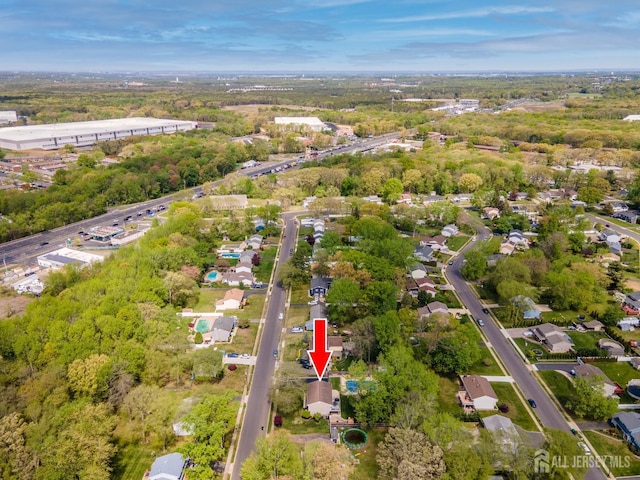 aerial overview of property's location with a tree filled landscape and nearby suburban area