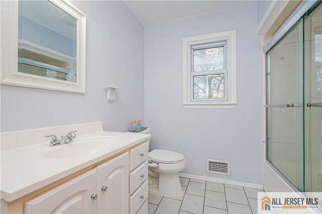 full bathroom with bath / shower combo with glass door, vanity, toilet, and tile patterned flooring