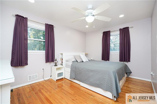 bedroom with multiple windows, hardwood / wood-style flooring, and ceiling fan