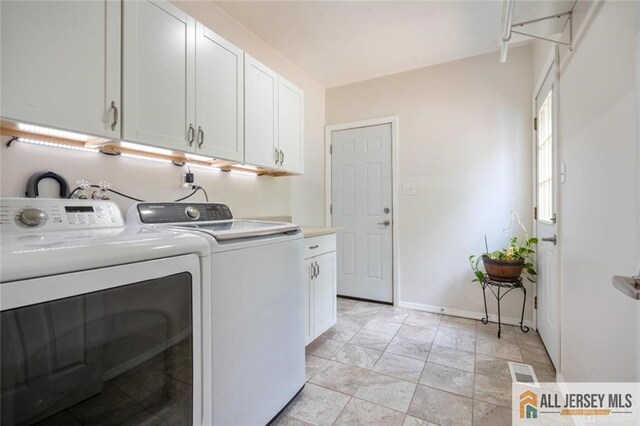 clothes washing area featuring cabinets and washer and dryer