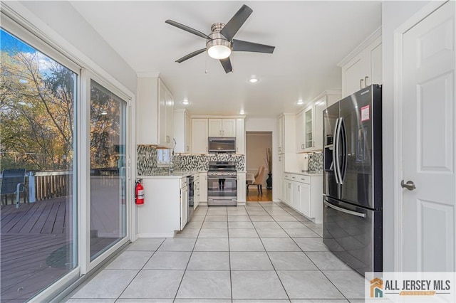 kitchen featuring light tile patterned flooring, white cabinets, backsplash, ceiling fan, and stainless steel appliances