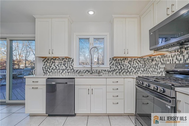 kitchen featuring white cabinetry, appliances with stainless steel finishes, sink, and light tile patterned flooring