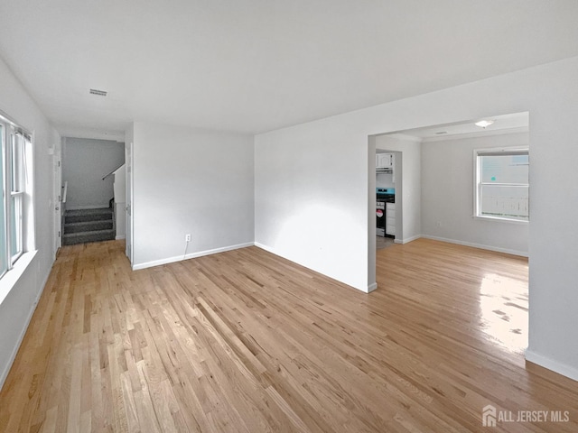 unfurnished living room featuring light wood-style floors, stairs, and baseboards